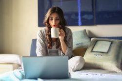 woman-in-grey-jacket-sits-on-bed-uses-grey-laptop-935743 (1)